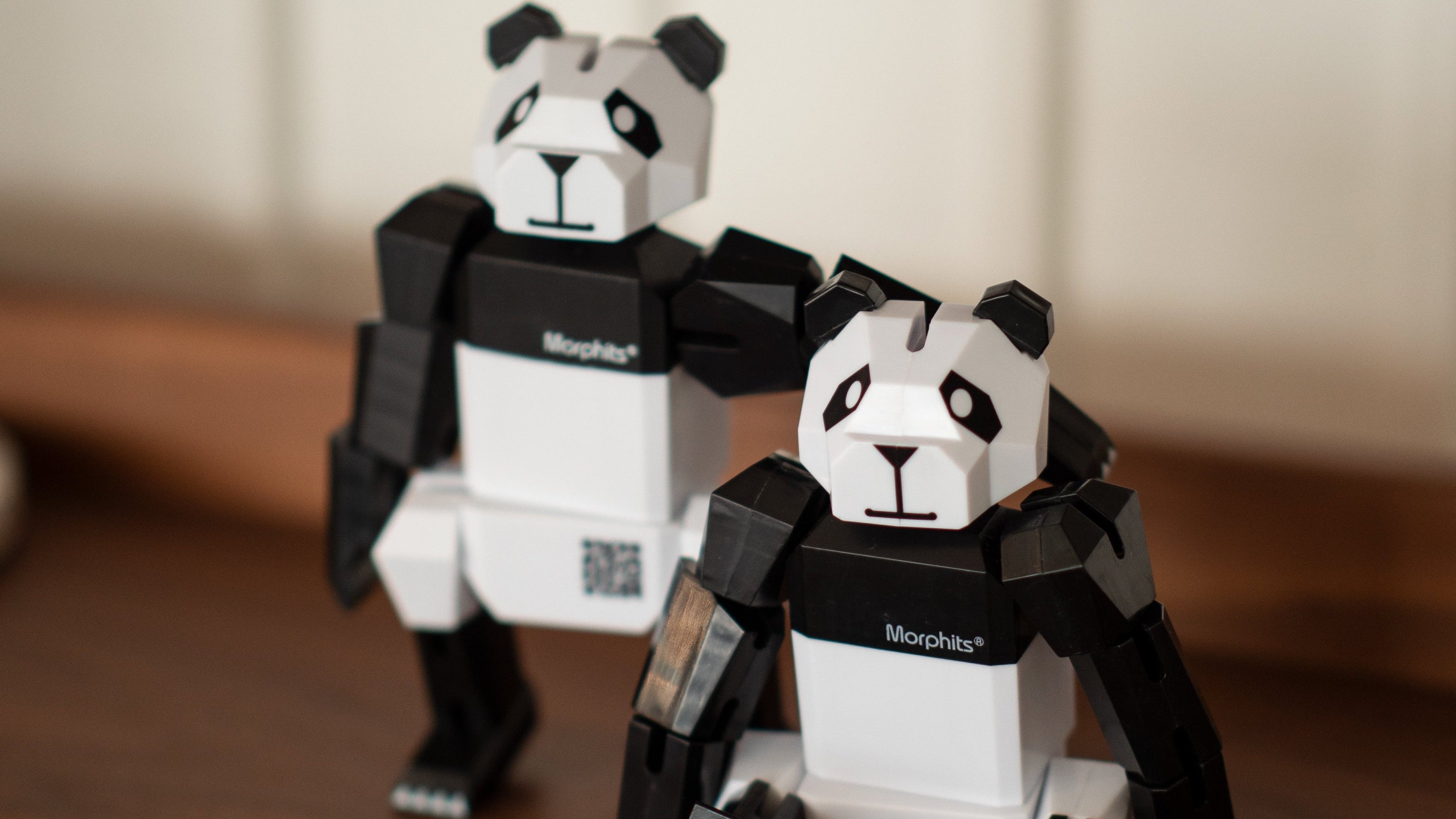 Two panda-shaped toys on a wooden surface with a blurred background